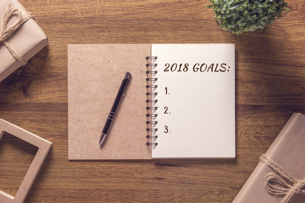 2018 goals list in notebook with gift box new year on wooden table background.
