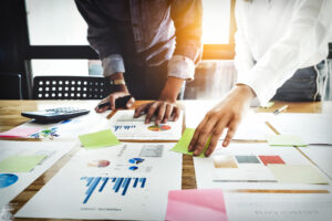 Business women and partners are analyzing the company's marketing plan with calculator on wood desk in the workplace.